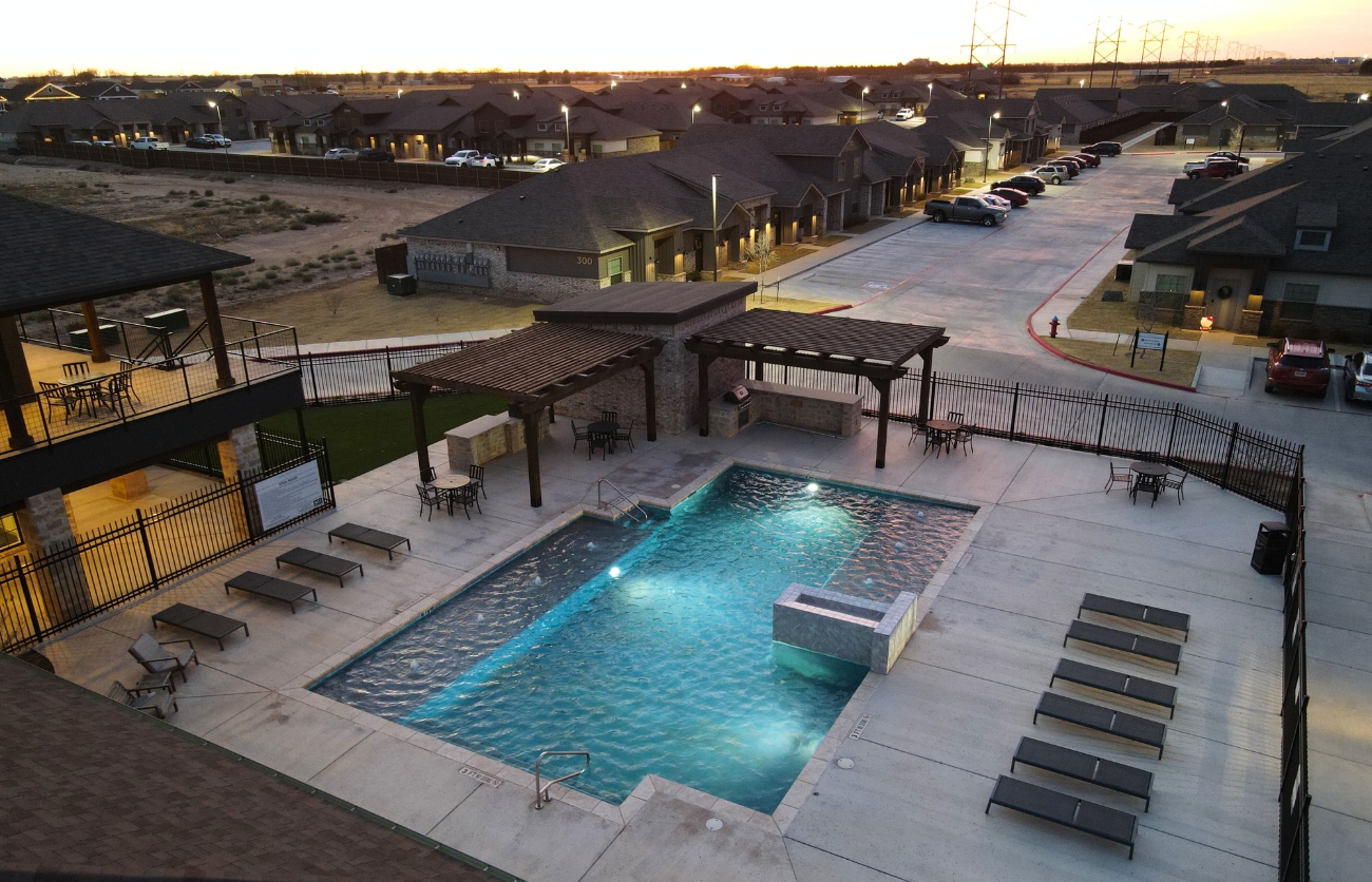 Modern outdoor pool area surrounded by luxury apartment buildings in Lubbock.